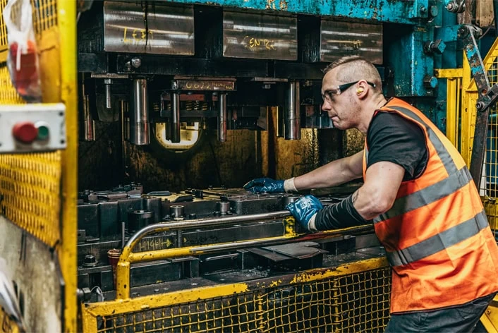 A man in an orange vest working on a machine.